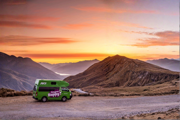Condo Campervan parked on top of mountain overlooking sunrise in NZ