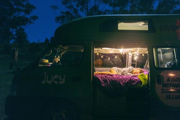 JUCY Condo parked at night with fairy lights on inside with girl sleeping