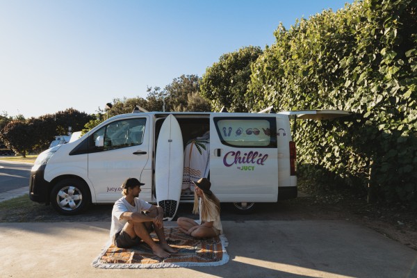 Chill'd Malibu Campervan hire parked at campground with couple having a picnic beside it