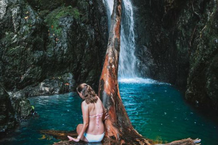 cairns to cape tribulation road trip itinerary 1 girl sits on a rock in front of fairy falls near cairns