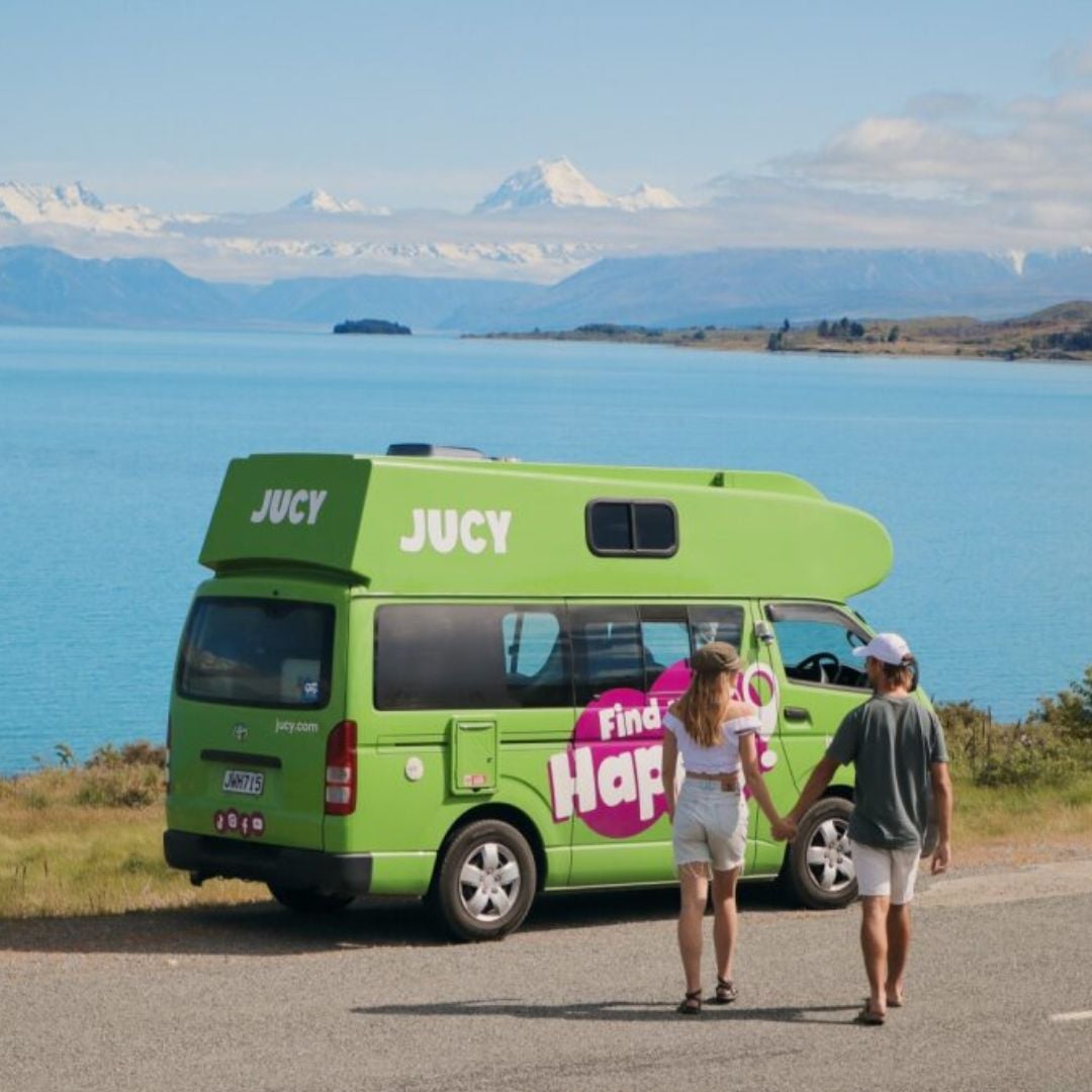 Couple walking toward JUCY condo parked next to lake takepo