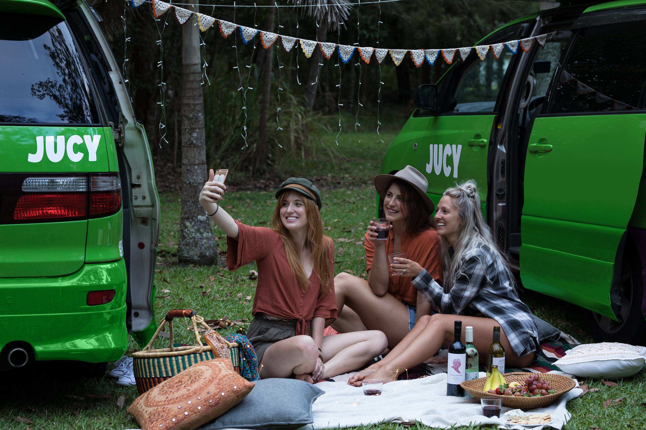 Group of girls enjoying a picnic outside their JUCY Campers