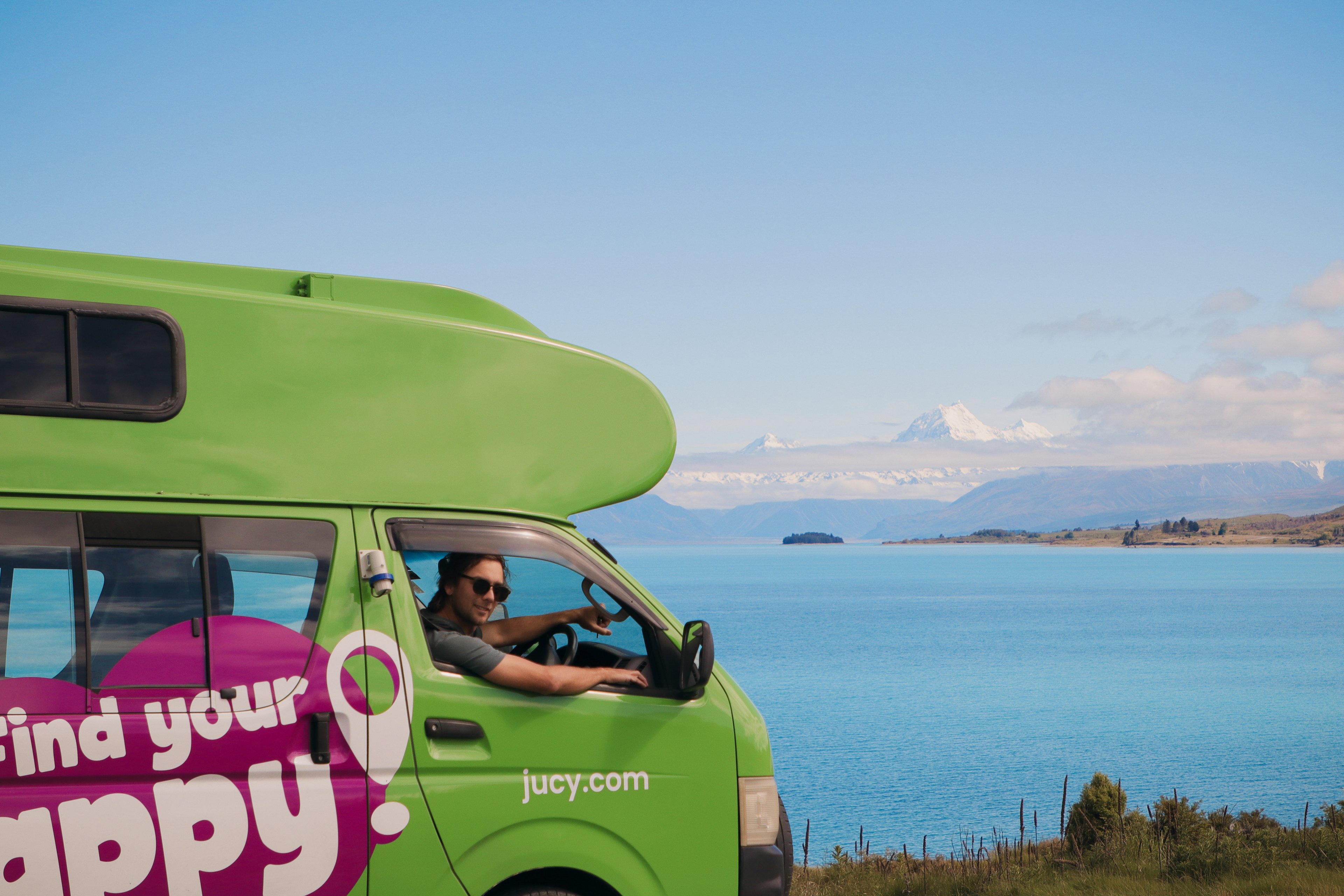 Man Driving JUCY Condo campervan hire next to lake