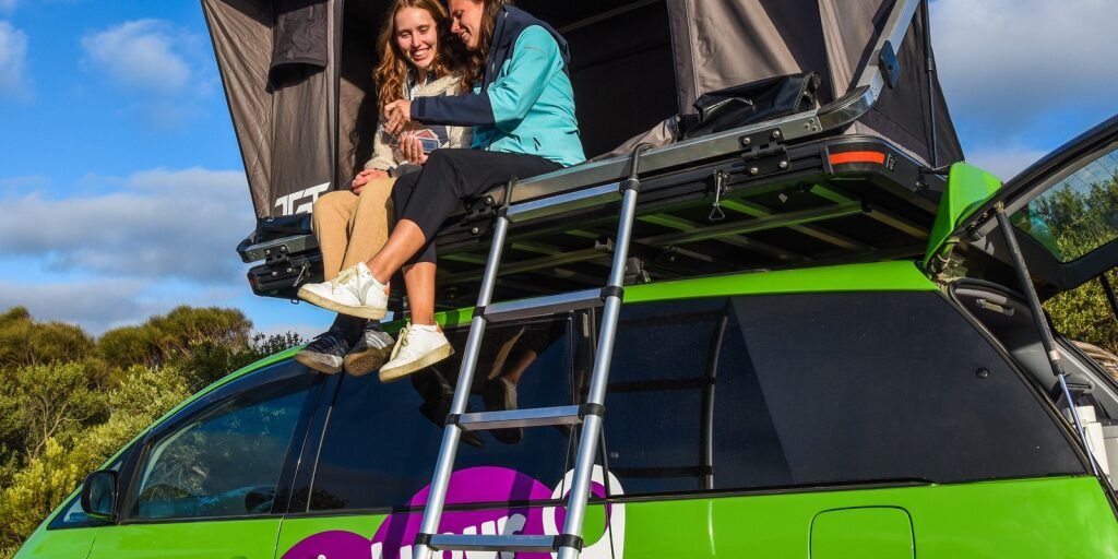 2 Ladies sitting inside the rooftop tent of the Crib Plus Campervan