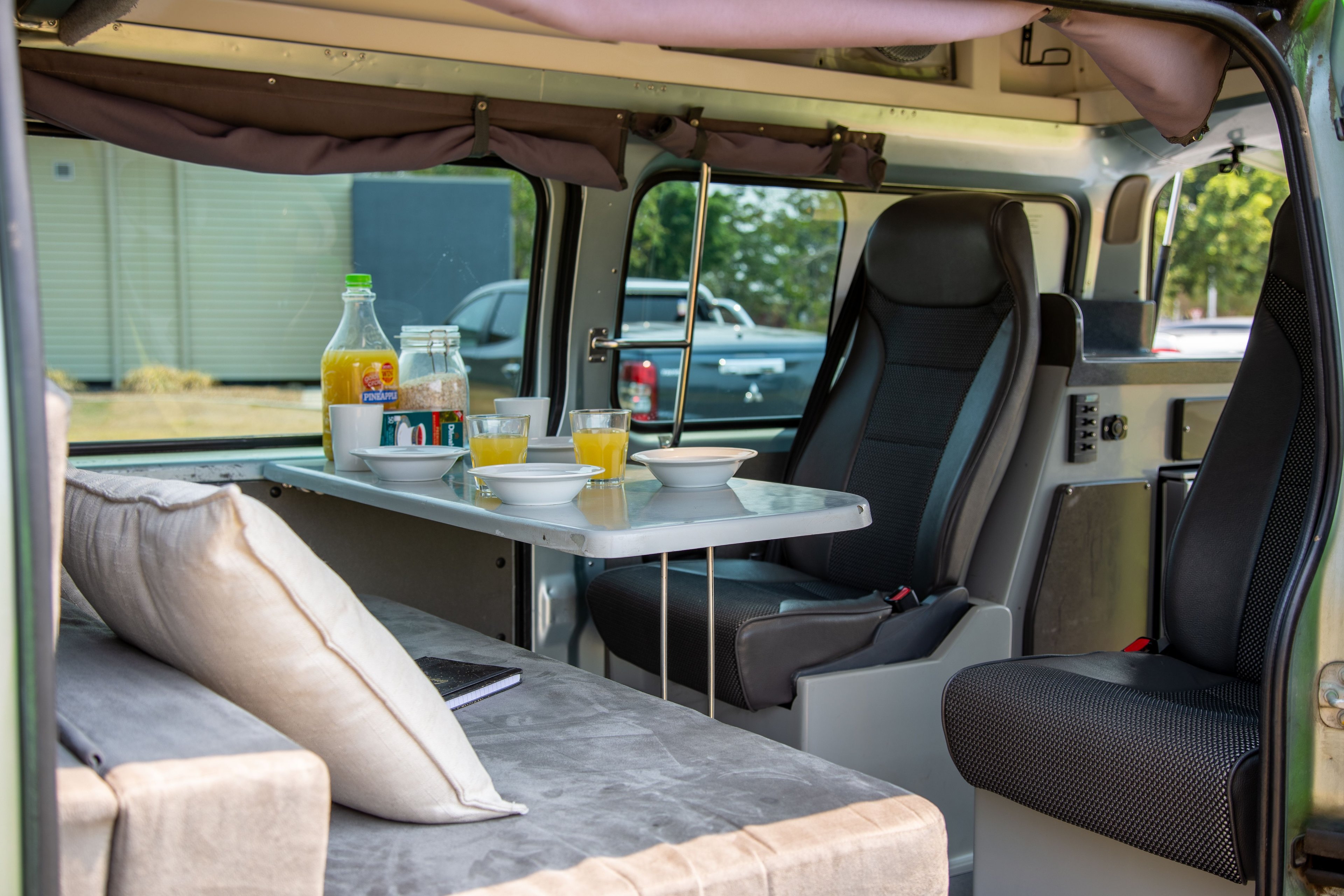 JUCY Condo campervan interior with table set up with breakfast spread out on it