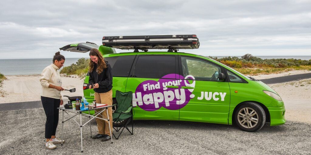 Crib Plus Campervan With 2 Women Using Camping Table To The Side